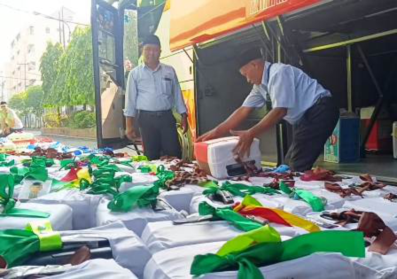 Petugas di Asrama Haji Surabaya saat merapikan koper jamaah.