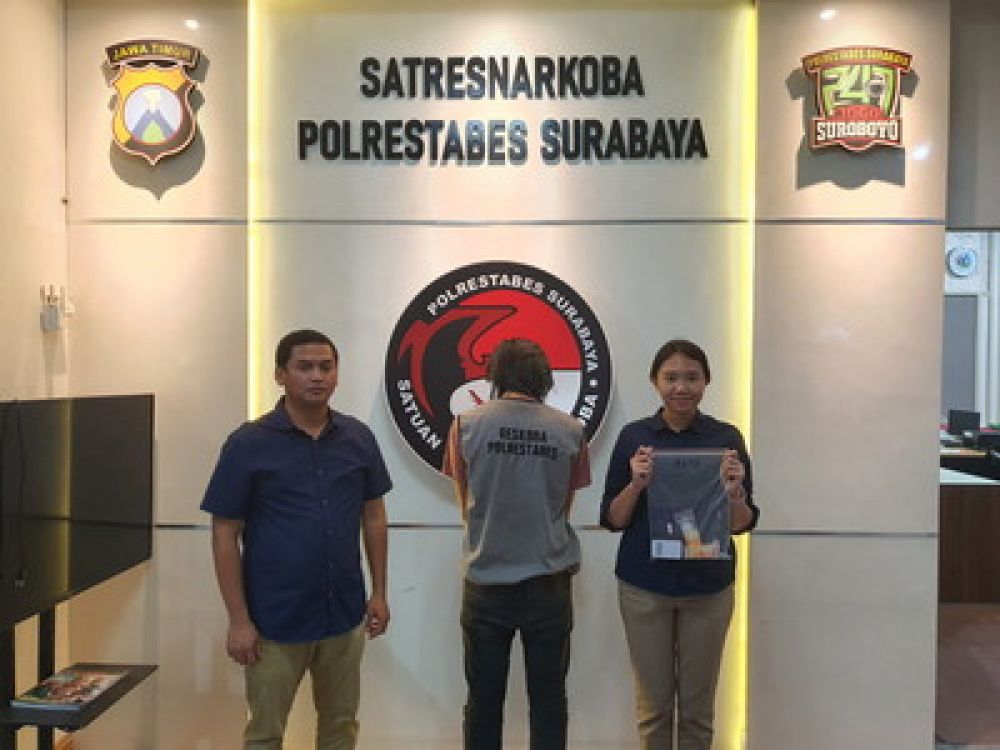 Tersangka ADS dengan foto punggung diapit dua petugas Sat Resnarkoba Polrestabes Surabaya.