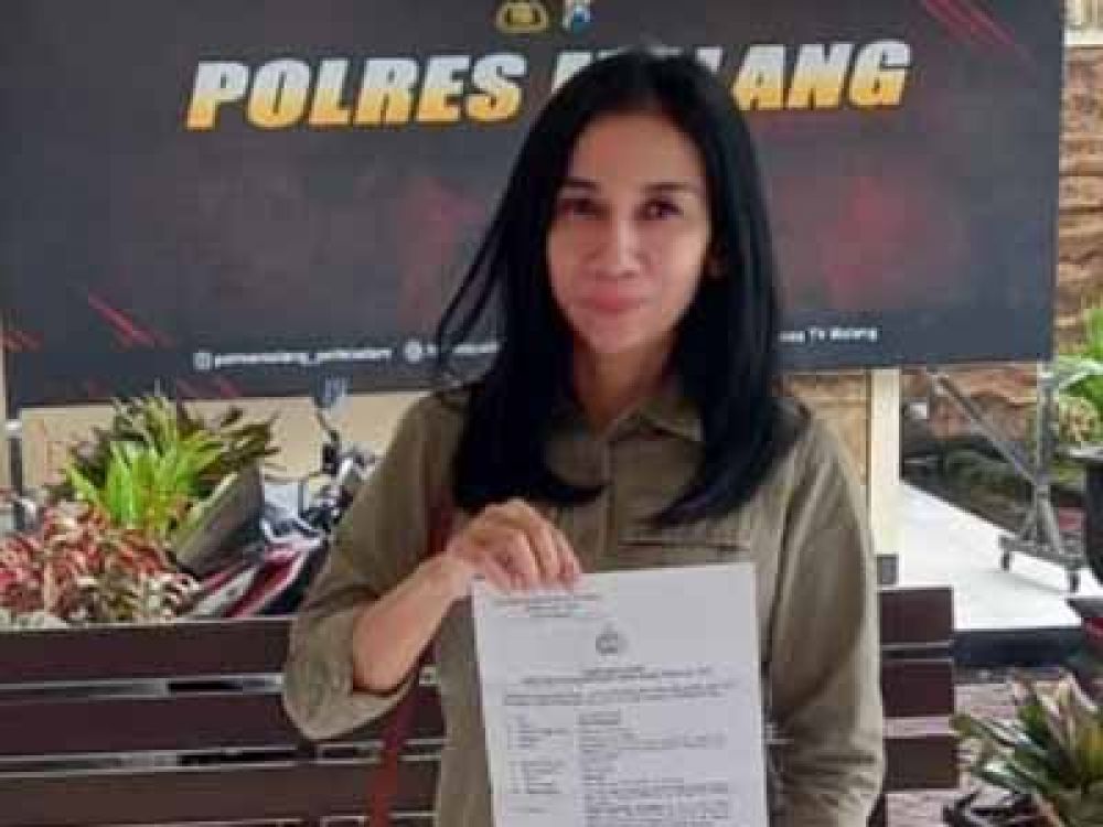 Rika Andriani menunjukkan bukti laporan polisi yang dibuatnya di Polres Malang atas dugaan tindak pidana penipuan yang dilakukan RHS bersama istrinya, Minggu, (20/11/2022).